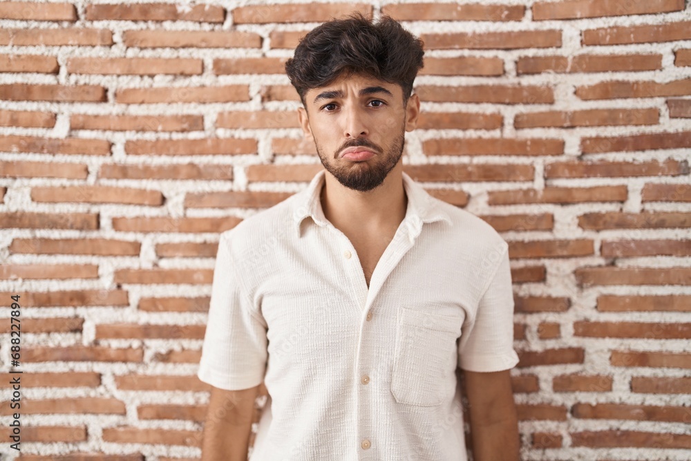 © Krakenimages.com - Arab man with beard standing over bricks wall background depressed and worry for distress, crying angry and afraid. sad expression.