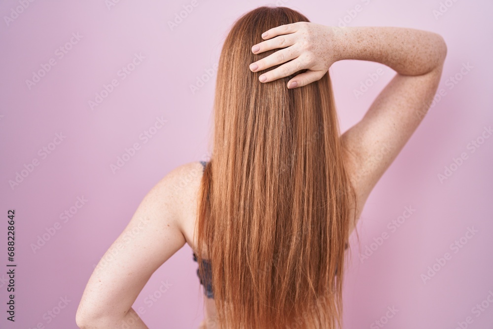 Naklejka premium Redhead woman wearing lingerie over pink background backwards thinking about doubt with hand on head