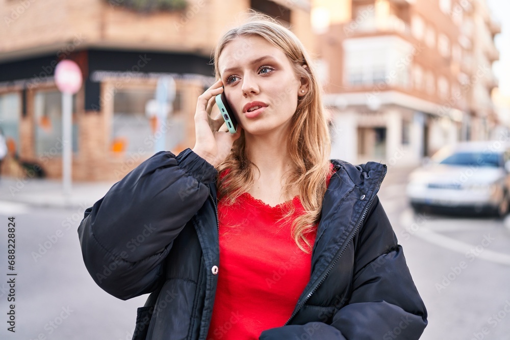 Young blonde woman talking on smartphone with serious expression at street Young blonde woman talking on smartphone with serious expression at street
