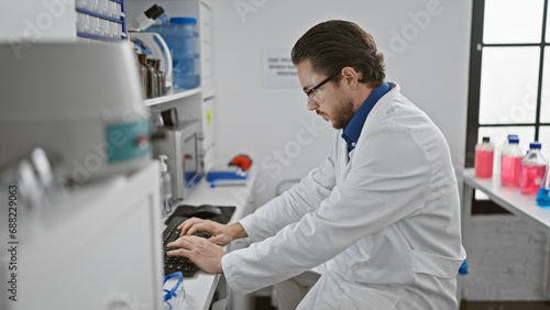 Young hispanic man scientist using computer at laboratory