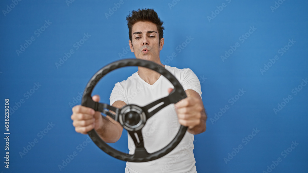 Obraz premium Young hispanic man smiling confident using steering wheel as a driver over isolated blue background