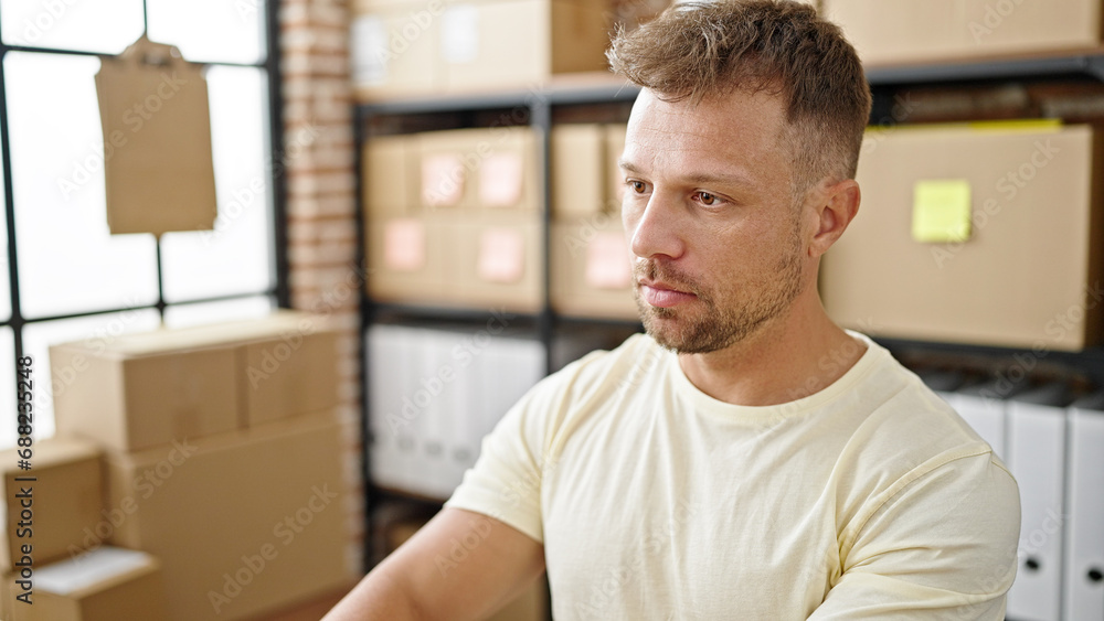 Young man ecommerce business worker sitting on table with relaxed expression at office Young man ecommerce business worker sitting on table with relaxed expression at office