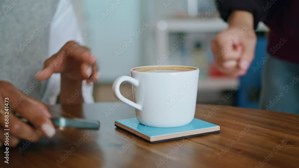 Barista putting cup coffee on table to woman sitting with smartphone closeup. Barista putting cup coffee on table to woman sitting with smartphone closeup.