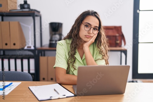 Young hispanic woman working at the office wearing glasses thinking looking tired and bored with depression problems with crossed arms. photo