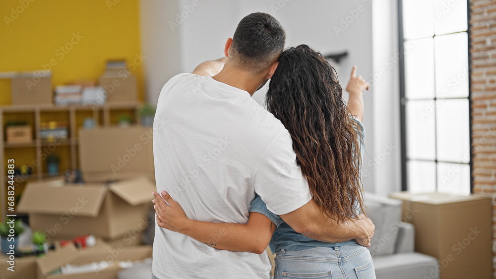 Man and woman couple hugging each other looking around standing backwards at new home Man and woman couple hugging each other looking around standing backwards at new home
