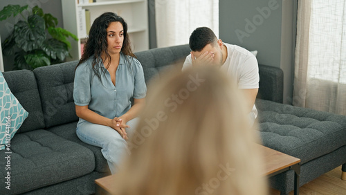 Man and woman sitting on sofa having couple therapy at psychology clinic photo