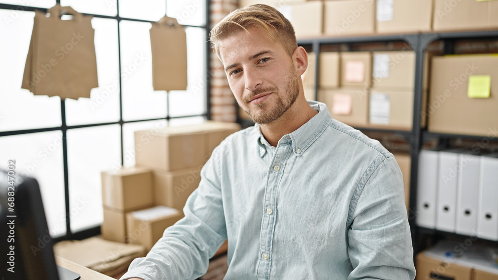 Young caucasian man ecommerce business worker sitting on table smiling at office Young caucasian man ecommerce business worker sitting on table smiling at office