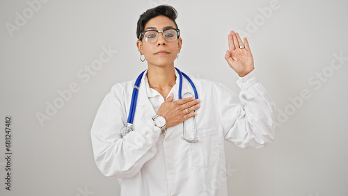 Photos Young beautiful hispanic woman doctor making an oath with hand on chest over iso