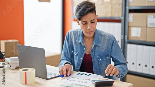 Young beautiful hispanic woman ecommerce business worker using calculator at office