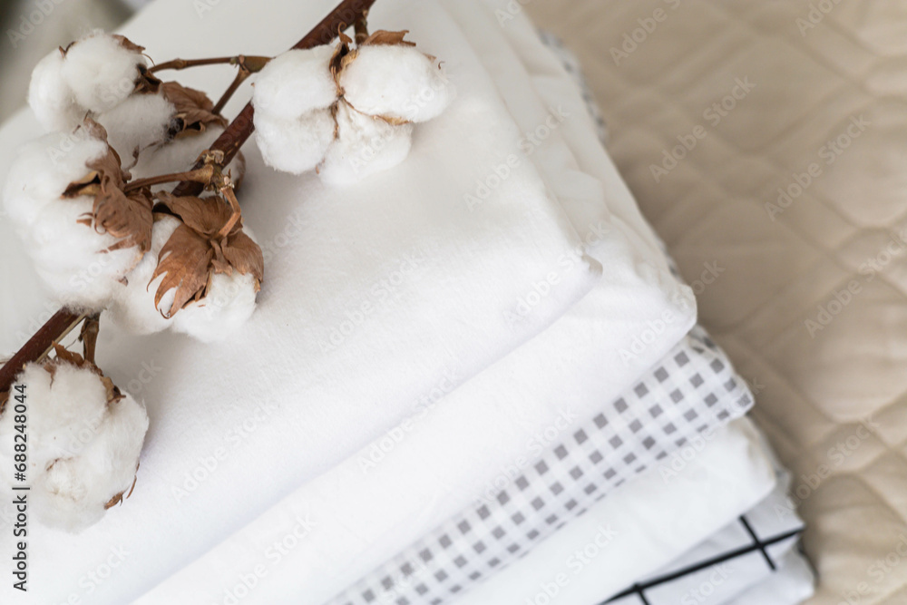 Cotton branch with pile of folded bed sheets and blankets Cotton branch with pile of folded bed sheets and blankets