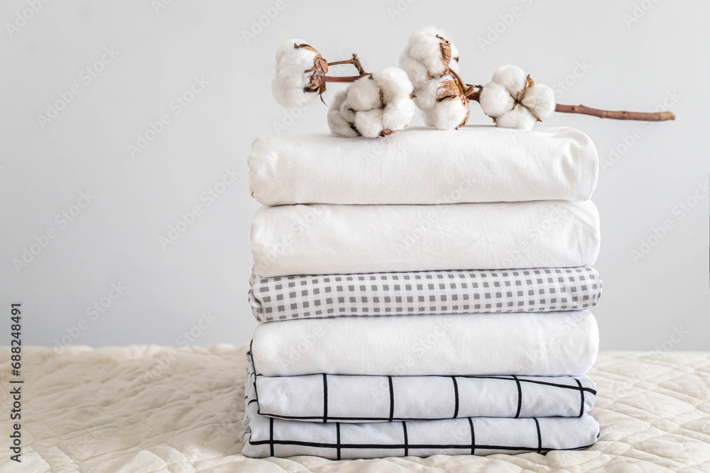 Cotton branch with pile of folded bed sheets and blankets - obrazy, fototapety, plakaty 