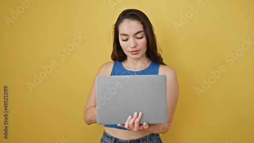 Young beautiful hispanic woman using laptop over isolated yellow background