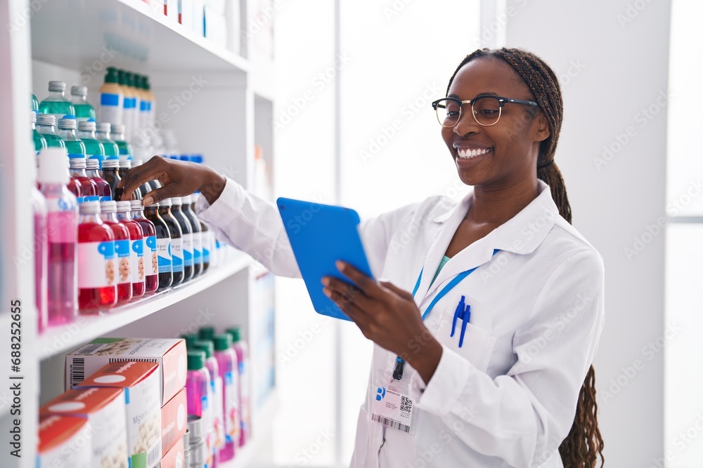 African american woman pharmacist using touchpad working at pharmacy