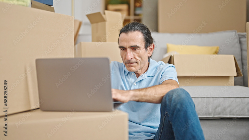Middle age man using laptop sitting on floor at new home Middle age man using laptop sitting on floor at new home