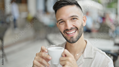 Young hispanic man smiling confident drinking coffee at coffee shop terrace photo