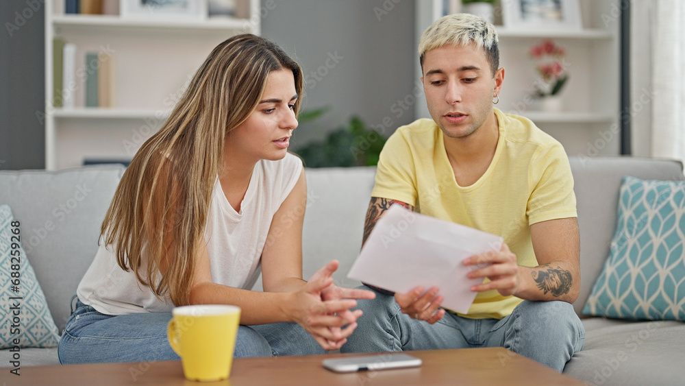 Beautiful couple reading document sitting on sofa at home Beautiful couple reading document sitting on sofa at home