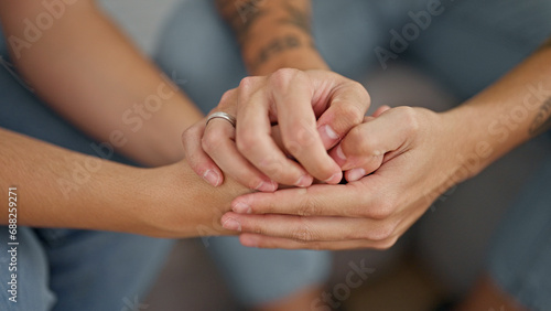 Hands of people sitting on sofa with hands together supporting at home