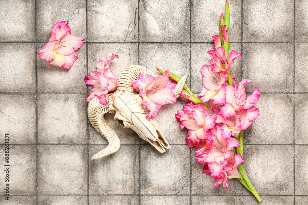 Skull of sheep with beautiful lily flowers on grey tile background