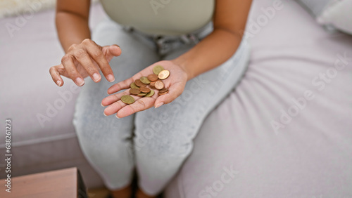 Close-up of a hardworking woman's hands carefully counting coins on a comfy sofa at home, maintaining her financial independence through savvy savings and investments photo