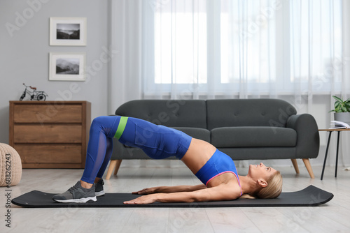 Athletic woman doing exercise with fitness elastic band on mat at home photo