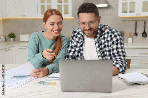 Couple using laptop for paying taxes online at home