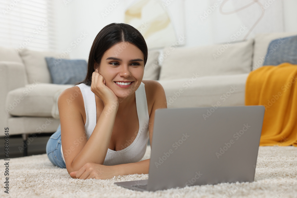 Happy young woman having video chat via laptop on floor in living room Happy young woman having video chat via laptop on floor in living room