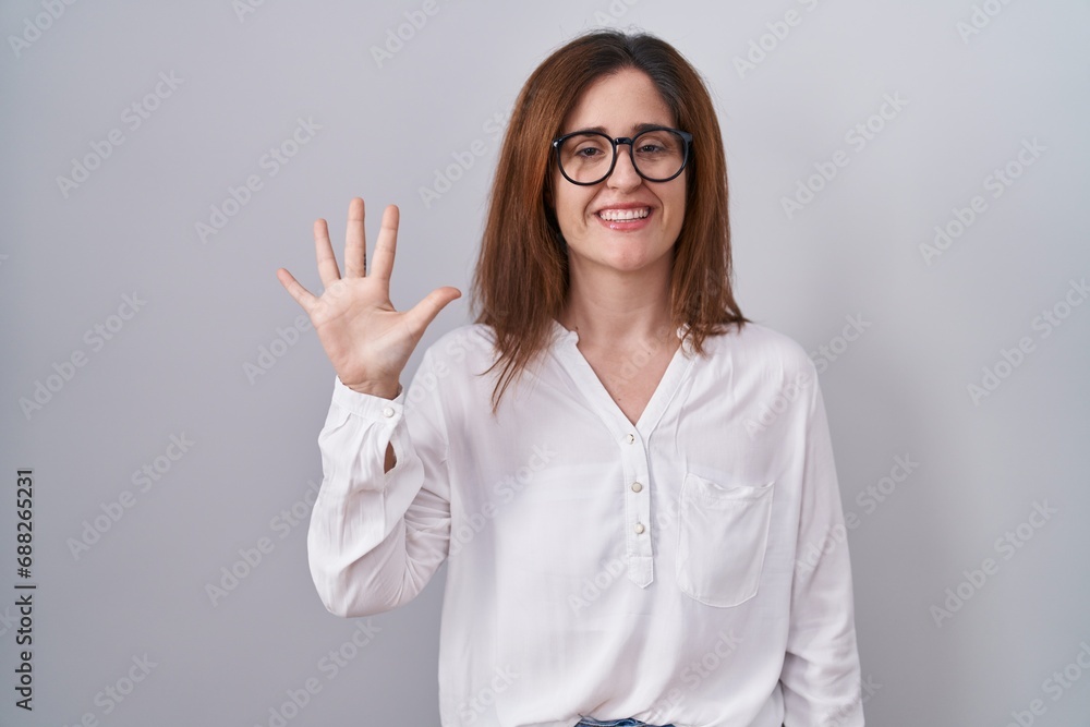 Brunette woman standing over white isolated background showing and pointing up with fingers number five while smiling confident and happy. Brunette woman standing over white isolated background showing and pointing up with fingers number five while smiling confident and happy.