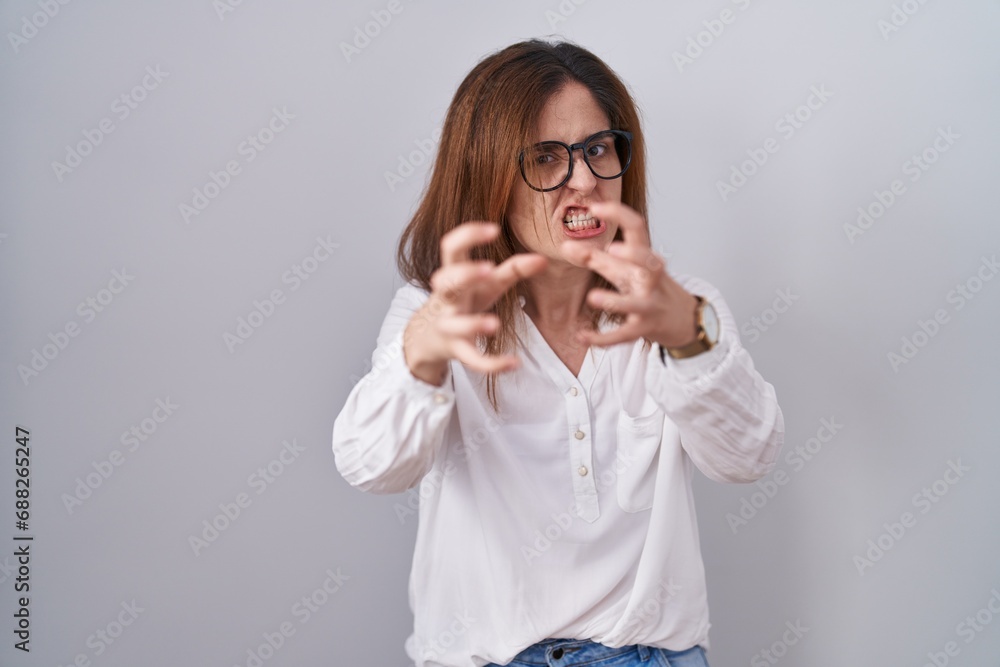 Brunette woman standing over white isolated background shouting frustrated with rage, hands trying to strangle, yelling mad Brunette woman standing over white isolated background shouting frustrated with rage, hands trying to strangle, yelling mad