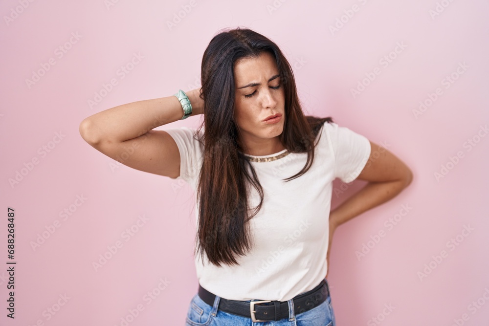 Young brunette woman standing over pink background suffering of neck ache injury, touching neck with hand, muscular pain Young brunette woman standing over pink background suffering of neck ache injury, touching neck with hand, muscular pain