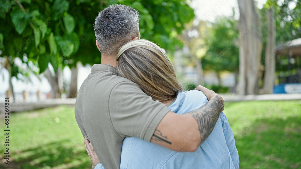 Man and woman couple hugging each other standing backwards at park Man and woman couple hugging each other standing backwards at park