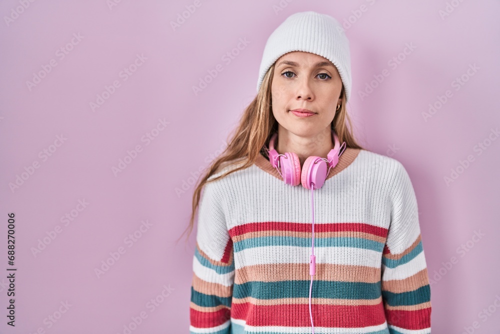 Young blonde woman standing over pink background relaxed with serious expression on face. simple and natural looking at the camera. Young blonde woman standing over pink background relaxed with serious expression on face. simple and natural looking at the camera.
