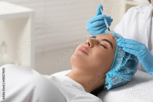 Doctor giving facial injection to young woman in clinic. Cosmetic surgery
