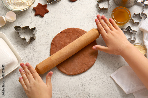 Woman rolling out gingerbread dough for Christmas cookies on grunge white background