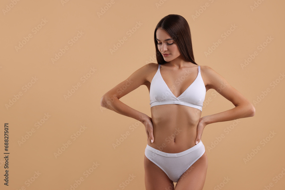 Fototapeta premium Young woman in stylish white bikini on beige background. Space for text