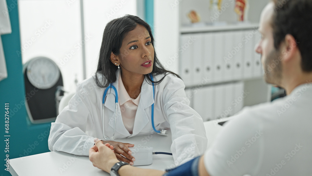 Doctor and patient sitting on table measuring pulse using tensiometer at the clinic Doctor and patient sitting on table measuring pulse using tensiometer at the clinic