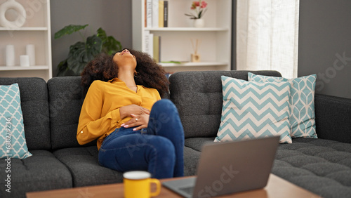 African american woman using laptop suffering for stomach pain at home