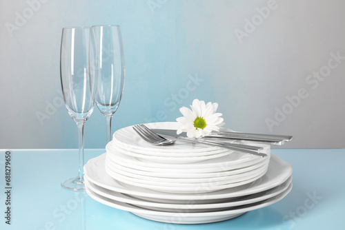 Set of clean dishes  glasses and cutlery on light blue table