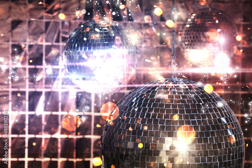 Shiny disco balls against foil party curtain under color lights, bokeh effect