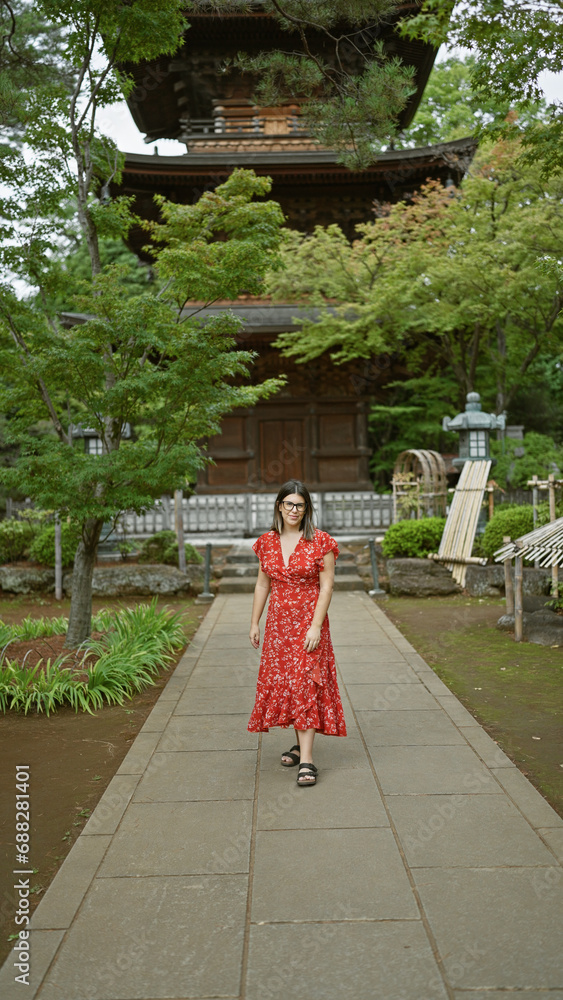 Burst of sunshine, beautiful hispanic woman with glasses, radiating happiness while leisurely walking at tokyo's gotokuji temple in casual summer style