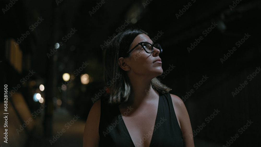 Fototapeta premium Cheerful beautiful hispanic woman in glasses enjoying kyoto's nightlife, looking around and smiling confidently on a lighted japanese street