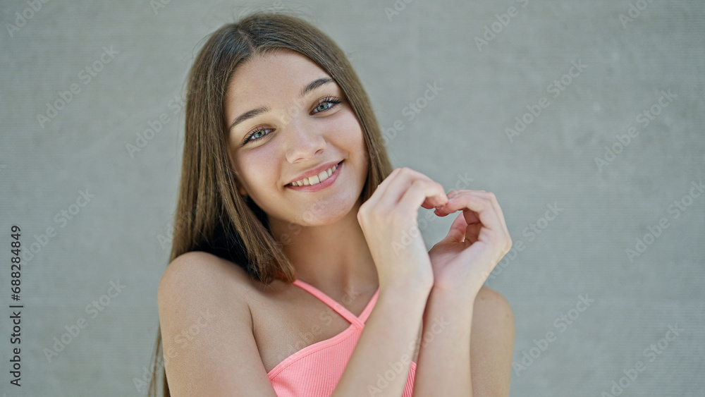 Young beautiful girl smiling confident doing heart gesture with hands over isolated white background Young beautiful girl smiling confident doing heart gesture with hands over isolated white background