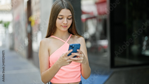 Young beautiful girl using smartphone with serious face at street