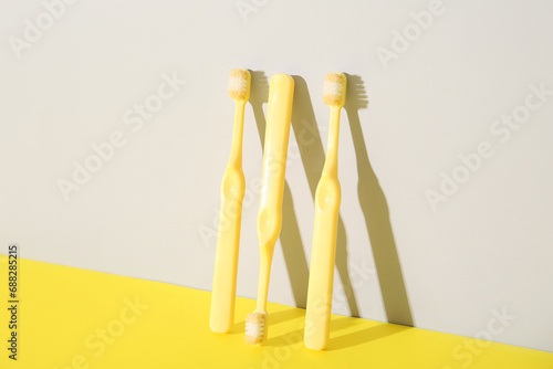 Three yellow toothbrushes on color background.