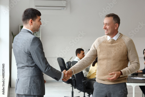 Business colleagues shaking hands in office