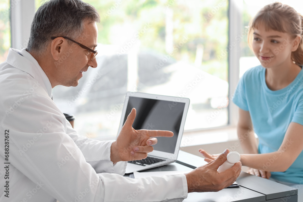 Mature doctor prescribing pills to female patient at table in medical office Mature doctor prescribing pills to female patient at table in medical office
