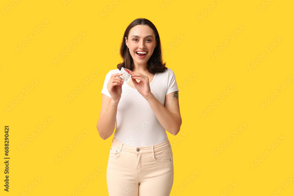 Beautiful young woman with open condom on yellow background. Safe sex concept Beautiful young woman with open condom on yellow background. Safe sex concept