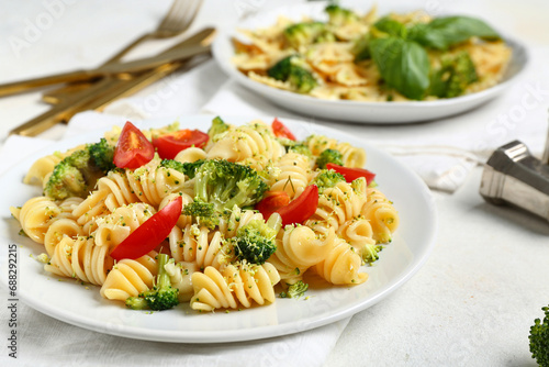 Plate of tasty pasta with broccoli and tomatoes on white background