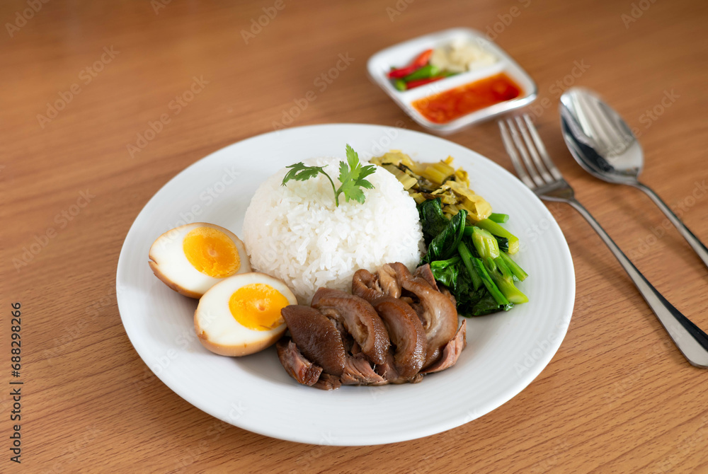 Stewed pork leg with boiled egg and rice on white plate. Stewed pork leg with boiled egg and rice on white plate.
