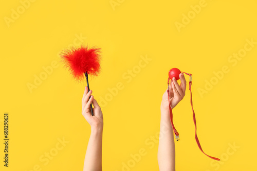 Woman holding sex toys on yellow background photo