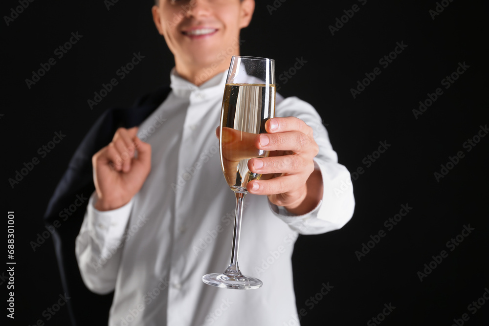 Young man with glass of champagne celebrating Christmas on black background Young man with glass of champagne celebrating Christmas on black background
